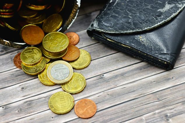 Imagem de várias moedas sobre uma mesa de madeira, simbolizando uma das oferendas para a Pombagira Maria Quitéria da Umbanda.