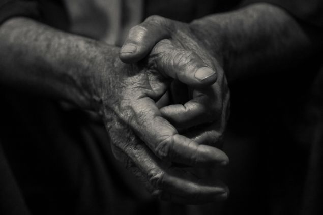 Imagem das mãos de uma pessoa idosa fazendo uma oração.
