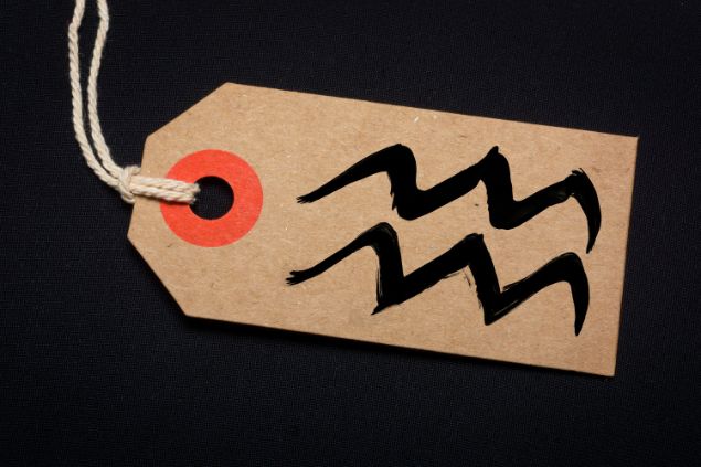 Imagem de fundo preto e em destaque uma etiqueta com o glifo de aquário.