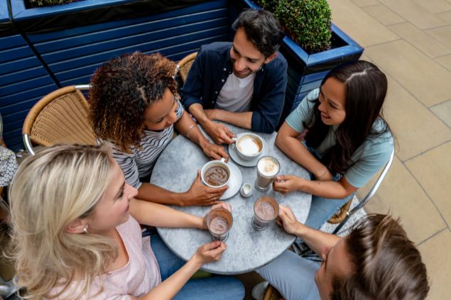 Imagem de várias pessoas reunidas em um café conversando. Elas representam o signo de gêmeos.