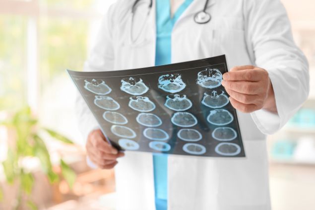 Imagem de um médico analisado exames neurológicos de um paciente.