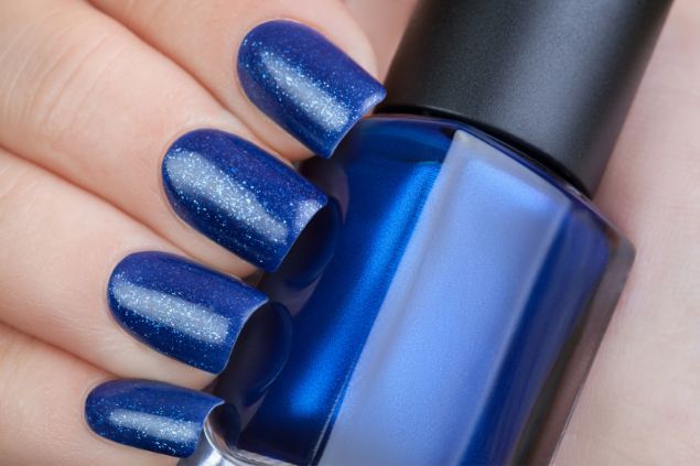 Imagem de uma mão com as unhas pintadas na cor azul.