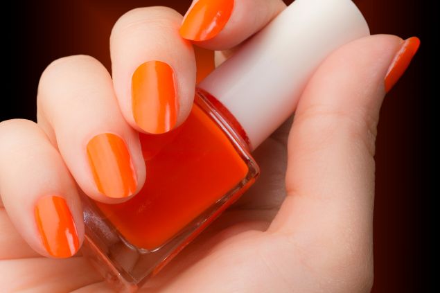 Imagem de uma mão com as unhas pintadas na cor laranja