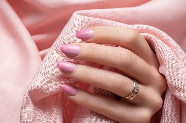 Imagem de uma mão com as unhas pintadas na cor rosa.
