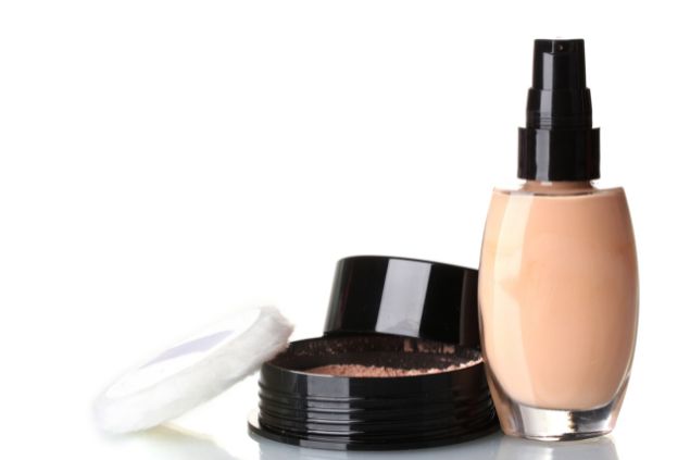 Imagem de um frasco de base e um estojo de pó compacto para o rosto, simbolizando os cosméticos do signo de sagitário.