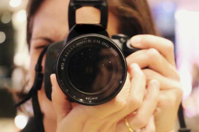 Imagem de uma mulher seguranda uma câmera fotográfica para fazer fotos, que é uma das habilidades do signo de leão.