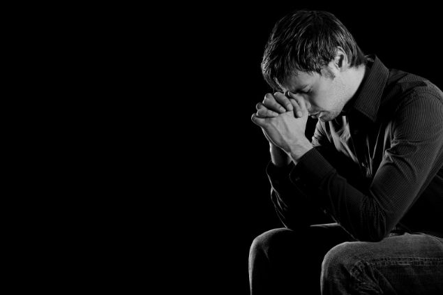 Imagem de fundo preto e em destaque um homem fazendo a sua oração.