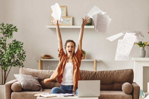 Imagem de uma mulher sentada no sofá lendo os roteiros de sua personagem. Ela joga vários papéis para cima.