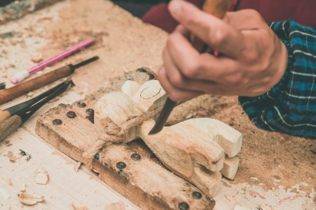 Imagem de uma pessoa fazendo uma escultura artesanal em madeira.
