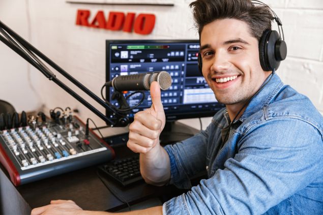 Imagem de um radialista em sua mesa de trabalho dentro da rádio.