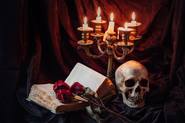 Imagem de um altar com velas, livro antigo, rosas vermelhas e uma caveira, simbolizando o Exu-Caveira na Umbanda.