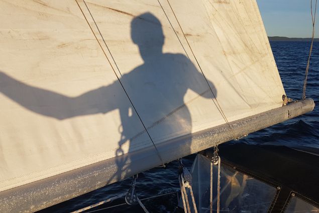 Imagem da sombra de um marinheiro na vela de um barco.
