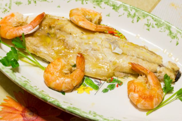 Imagem de um prato com peixe e camarões, tipo de oferenda para os Marinheiros.