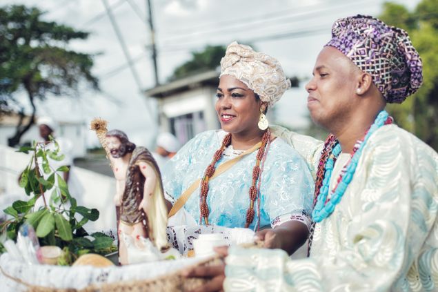 Imagem de um casal de baianos segurando uma oferenda durante uma cerimônia religiosa em Salvador.