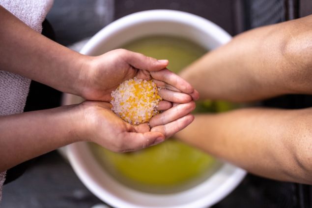 Imagem de uma pessoa se preparando para o ritual do batismo na Umbanda. Ela está se lavando com sais e ervas.