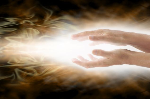 Imagem de duas mãos sobre um feixe de luz. A foto traz o conceito de cura energética pela cabocla Iara.