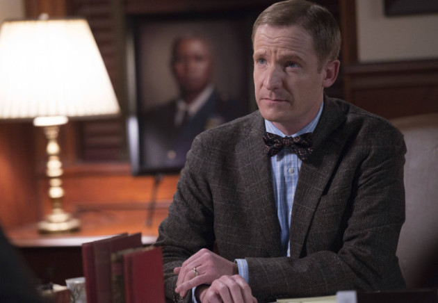 Homem branco vestindo terno cinza.