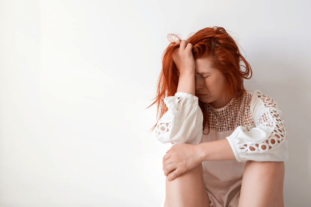 Mulher sentada apoiando o rosto sob a mão direita