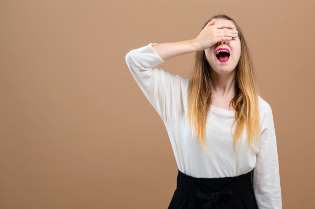 Mulher com a mão sobre o rosto, com feição de decepção, após cometer erro.