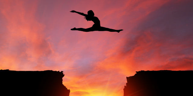 Mulher com pernas e braços erguidos pula sobre abismo.