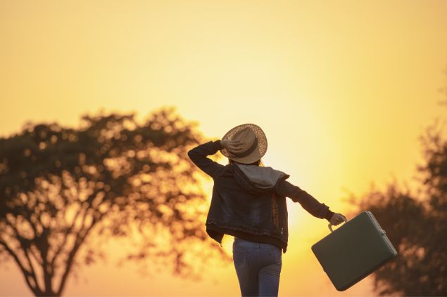 Mulher com mala de viagem caminhando.