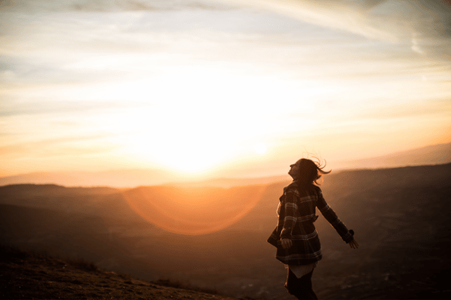 Mulher no campo de braços abertos