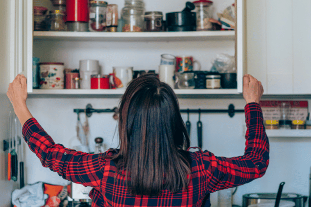 Mulher organizando um armário na cozinha