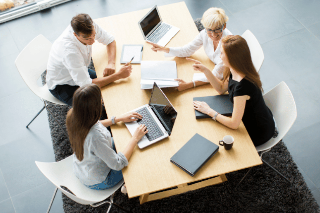 Pessoas sentadas trabalhando juntas, em escritório. 
