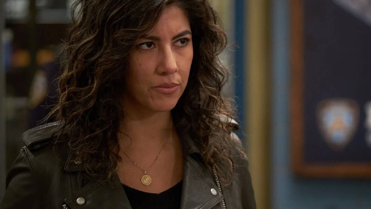 Mulher branca de cabelos ondulados e curtos com expressão séria.