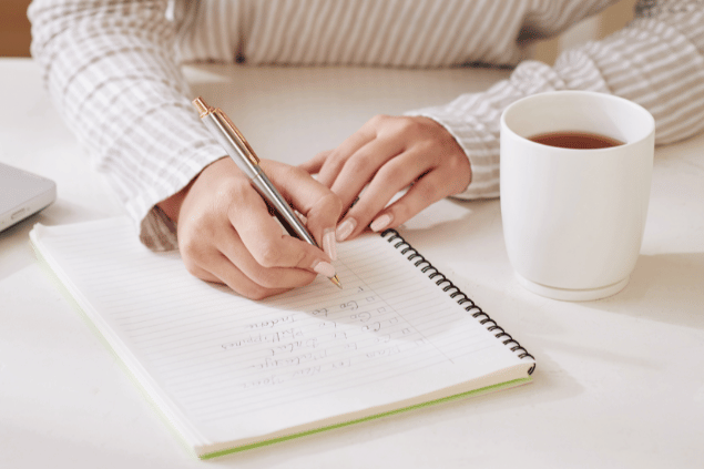 Jovem mulher escrevendo afirmações em caderno. Exercício de autoestima.
