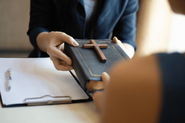 Mãos femininas entregando bíblia para uma mulher. 