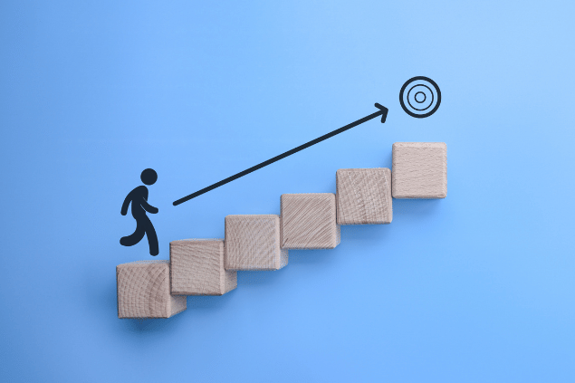 Conceito de ambição, de objetivos a serem alcançados. Um bonequinho está subindo uma escada para alcançar o seu alvo. 