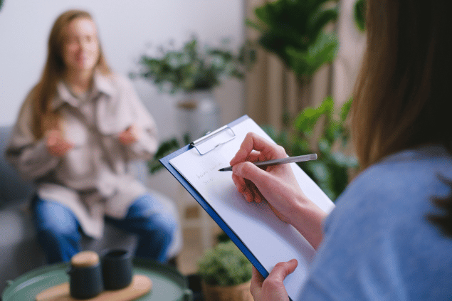 Psicóloga fazendo notas da conversa com sua paciente, durante a sessão de terapia. 