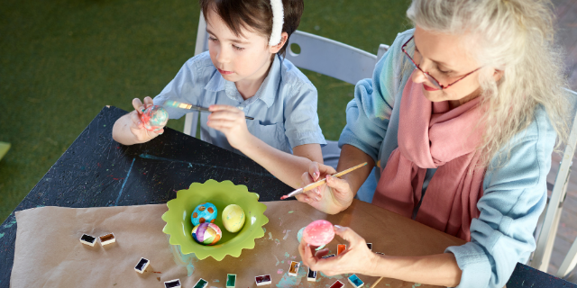 Mulher e criança pintam ovos de páscoa.