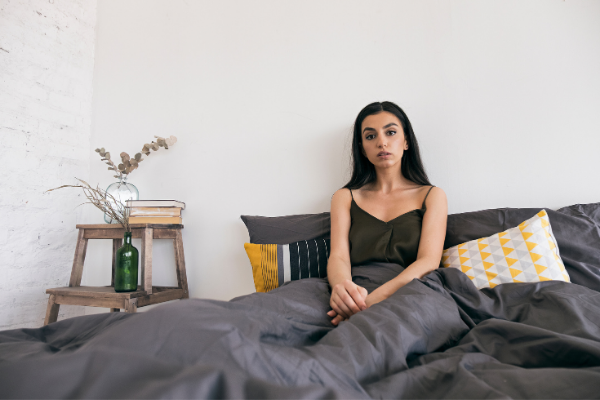 Mulher sentada na cama com expressão de concentração