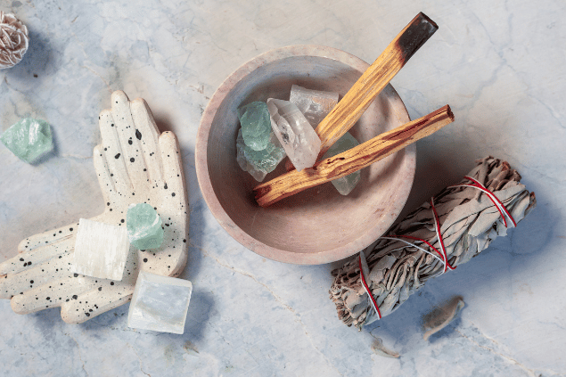Na imagem, há um recipiente com cristais e palo santo.