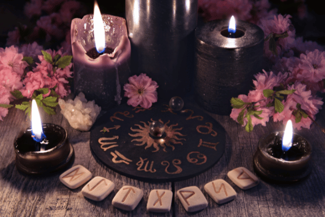 Vera Petruk / Canva Na imagem, há velas, flores e pedras em cima de uma mesa.