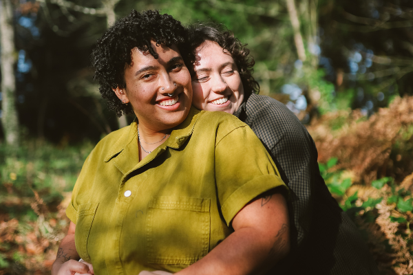 Casal se abraçando e sorrindo em um jardim ensolarado