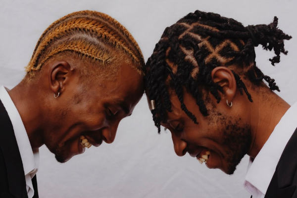 Casal de homens de frente com as cabeças encostadas. Os dois estão sorrindo