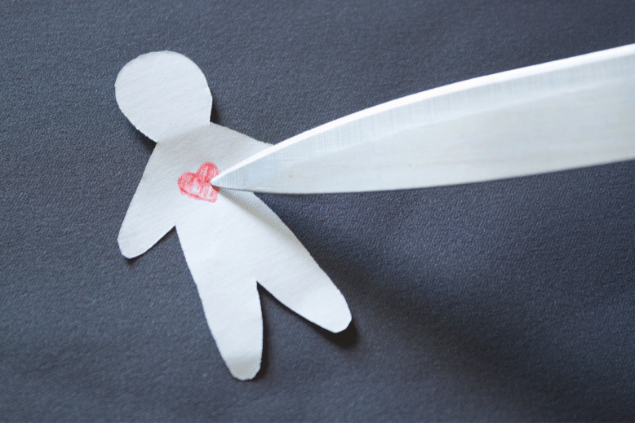 Faca apontando para um bonequinho de papel com coração vermelho. 