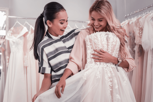 Mulheres felizes ao acharem um vestido de noiva.
