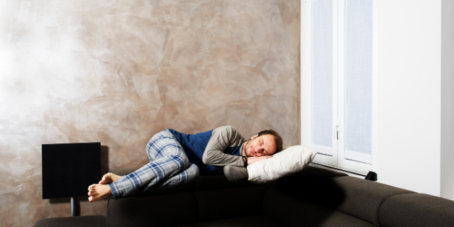 Homem dorme em sofá. 