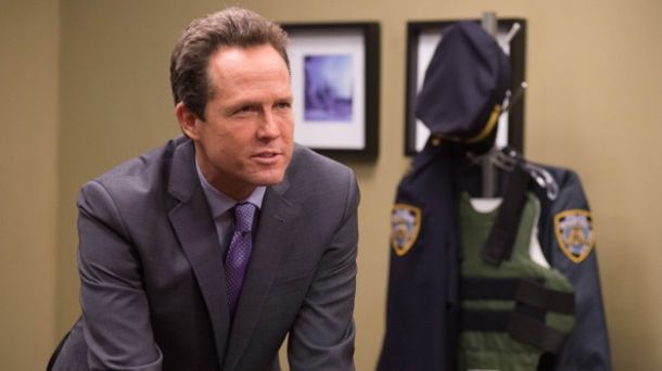 Homem branco vestindo terno cinza.