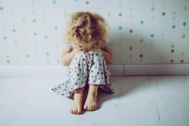 Criança sentada no chão, escondendo o rosto. Conceito de ressentimento.