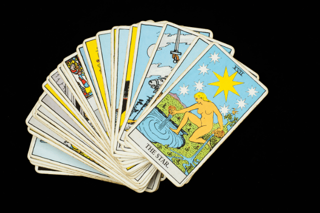 Várias cartas de Tarot estão dispostas em sequência sobre uma superfície. A carta A Estrela está destaque no final da sequência.