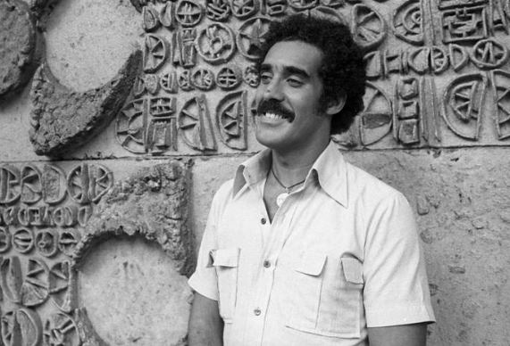 Homem negro de bigode e cabelos castanhos.