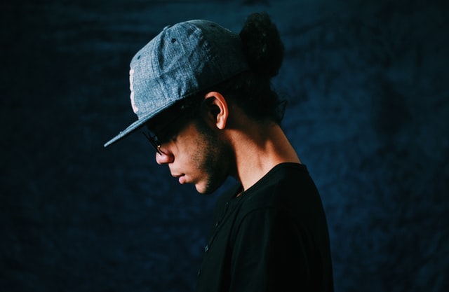 Homem branco de boné e cabeça baixa.