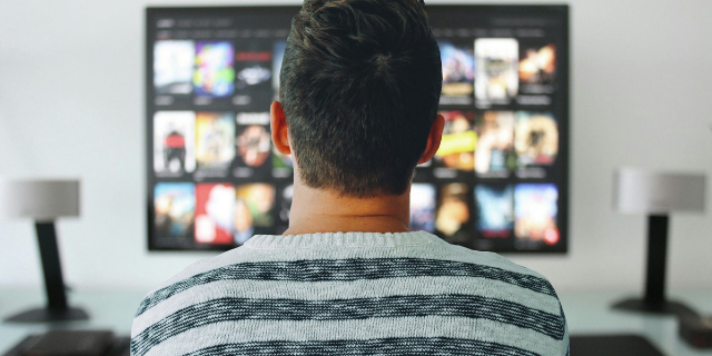 Homem sentado em frente à televisão.