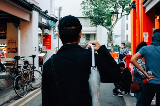 Homem segurando guarda-chuva transparente fechado.