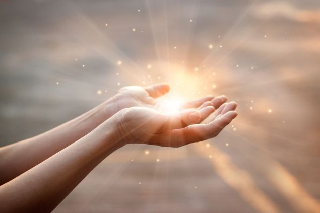 Mãos segurando uma luz em suas palmas.